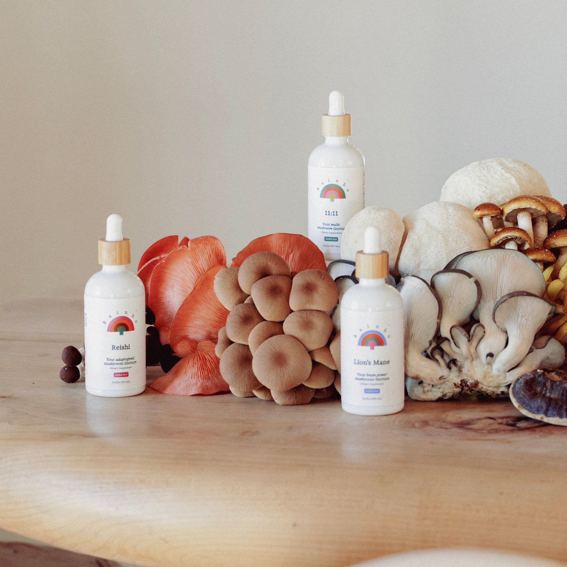 Three mushroom tincture bottles with droppers on a wooden surface with mushrooms.