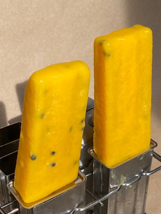 two orange popsicles are pictured with seeds in them from passion fruits